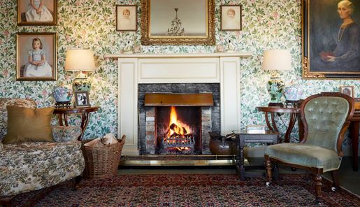 The ornate fireplace and wallpaper in the drawing room of the Kinloch Lodge in the Scottish Highlands